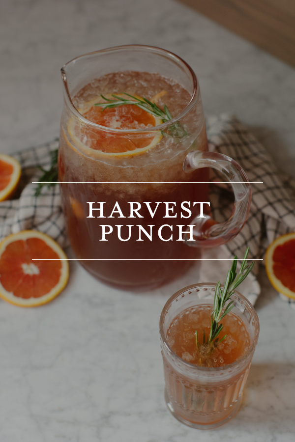 Refreshing harvest punch drink with orange slices and rosemary garnish in glass pitcher and glass, perfect for fall gatherings and seasonal entertaining at home.