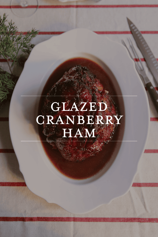 Cranberry Glazed Ham on a white platter at a dinner table