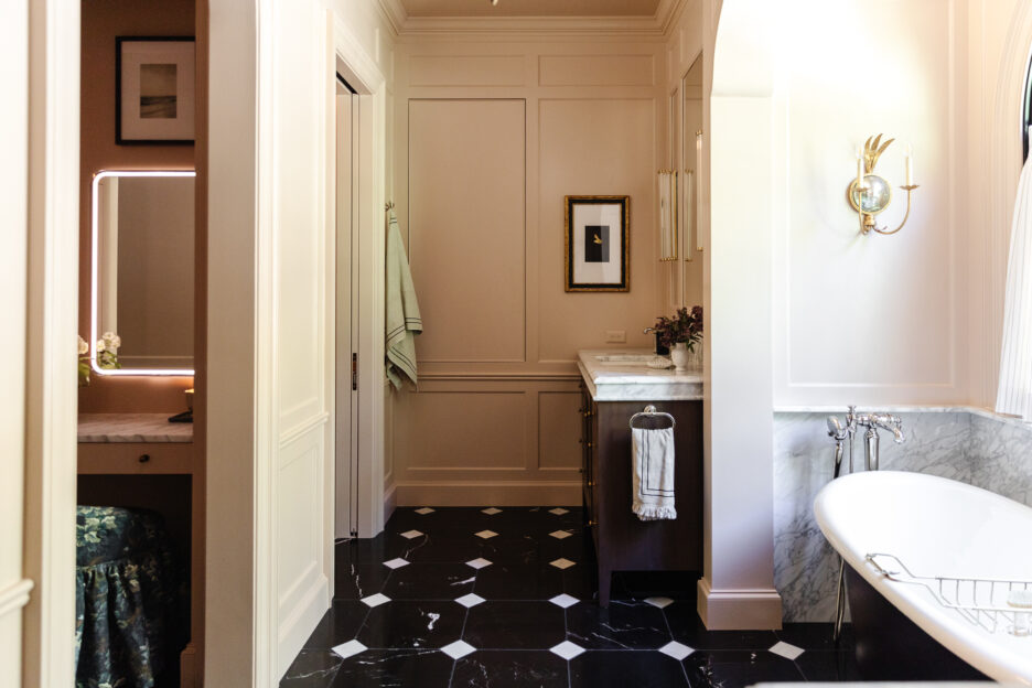 Stylish and classic bathroom interior featuring marble countertops, black marble flooring with white accents, a chic wall sconce, and tasteful artwork, perfect for home renovation ideas.