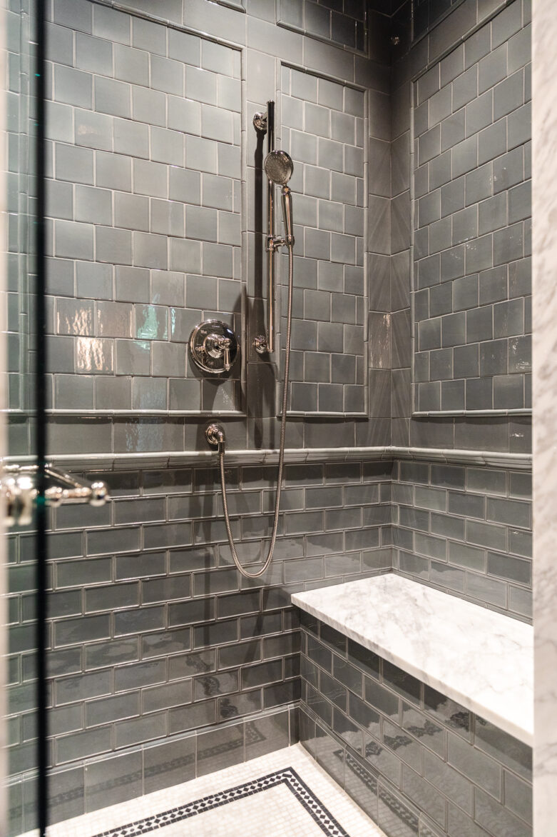 A sleek walk-in shower featuring gray subway tiles, marble bench, and contemporary fixtures, ideal for bathroom renovation inspiration.
