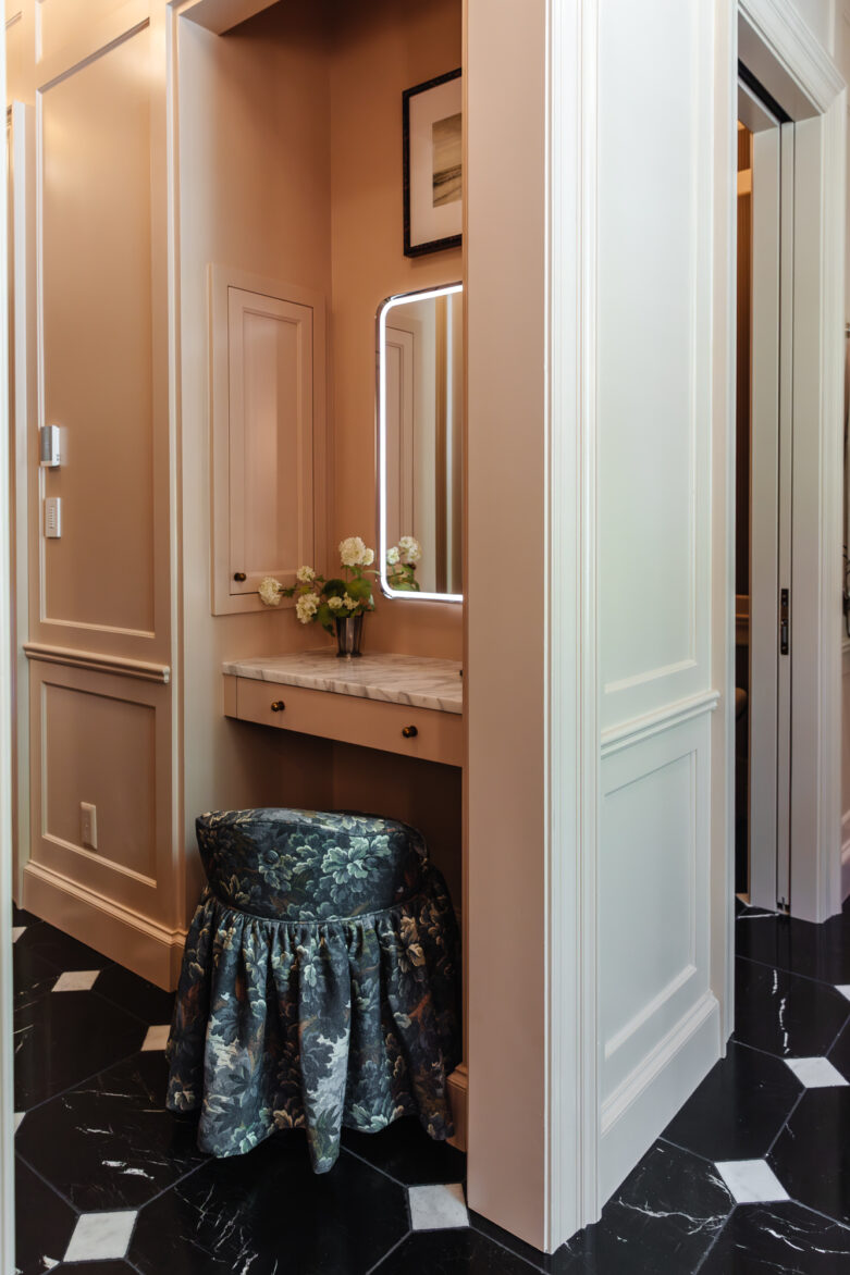 Graceful bathroom vanity with elegant marble-topped vanity, wall mirror with LED lighting, and vintage-inspired floral upholstered stool showcasing sophisticated home decor.