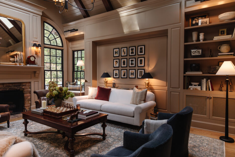 Luxurious living room with large arched windows, cozy sofa, elegant artwork, and curated décor, showcasing timeless interior design by Chris Loves Julia.
