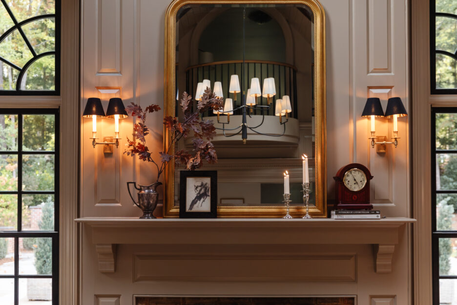 Vintage-inspired fireplace mantel with elegant wall sconces, a large gold-framed mirror, and cozy decor, showcasing timeless interior design and lighting ideas for a sophisticated living space.