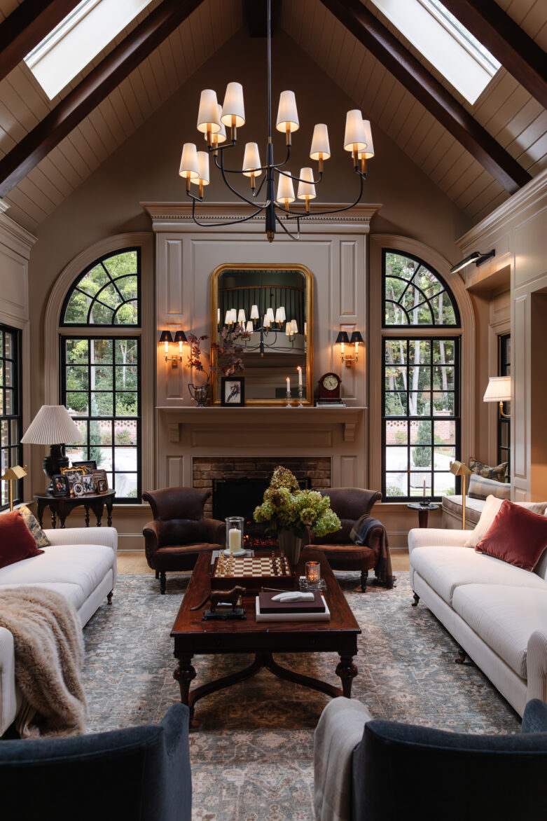 Cozy living room with elegant vaulted ceiling, chandelier, large windows, and classic decor, perfect for home renovation inspiration by Chris Loves Julia.