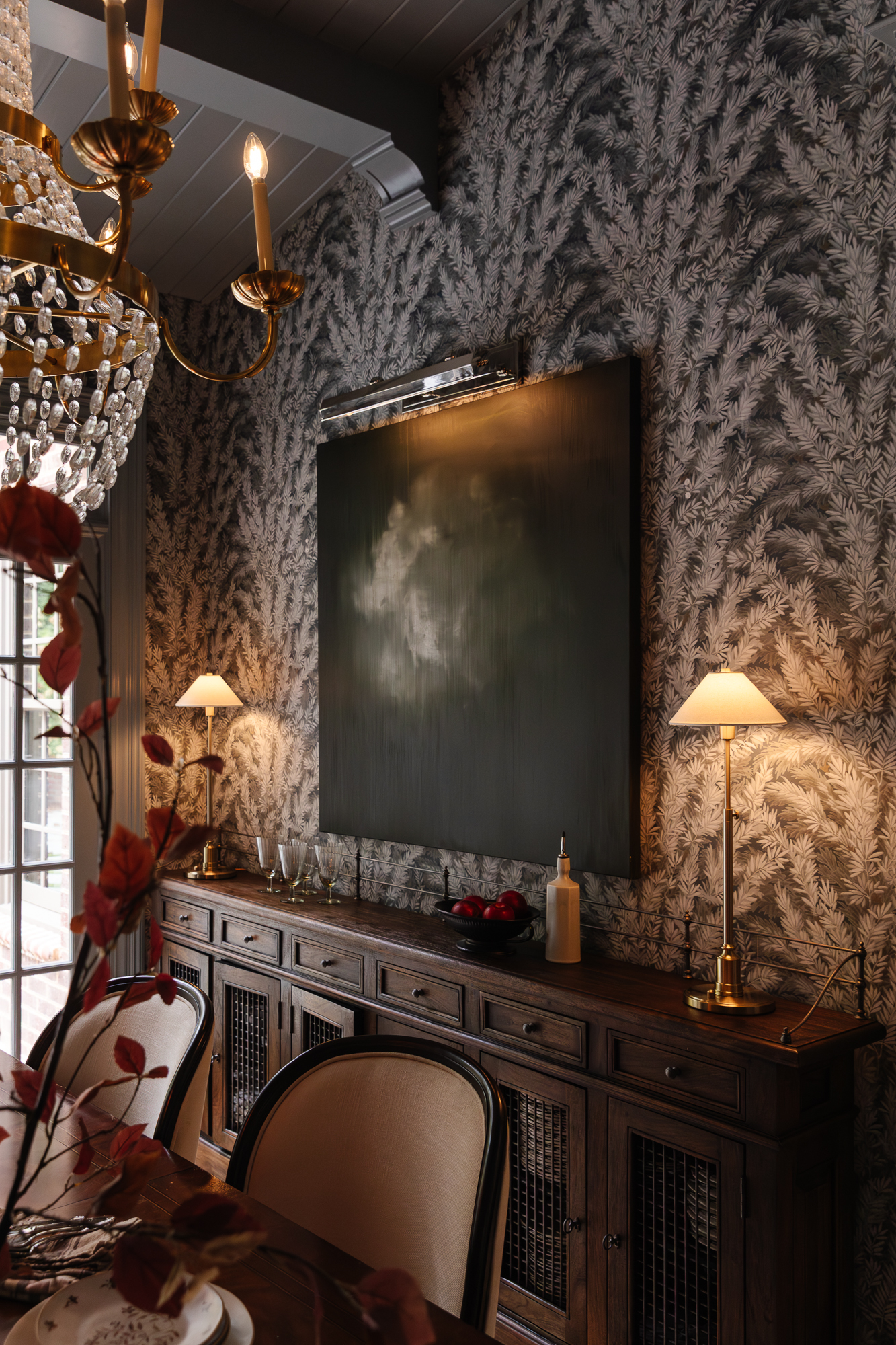 Chandelier and table lamps provide warm lighting in a sophisticated, cozy space.