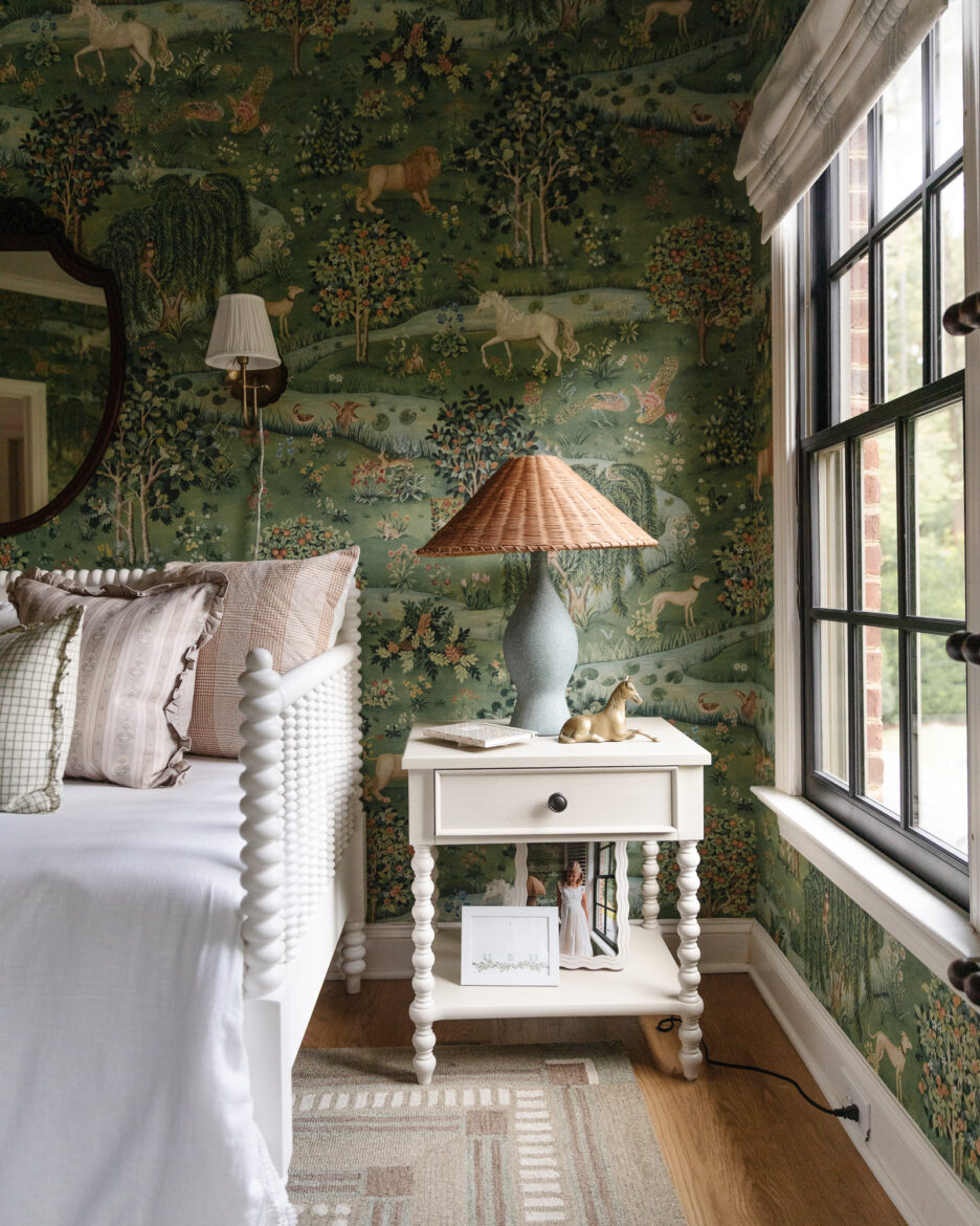 Vintage-inspired bedroom with whimsical forest-themed wallpaper, white bed with textured details, and cozy accessories for charming home decor.