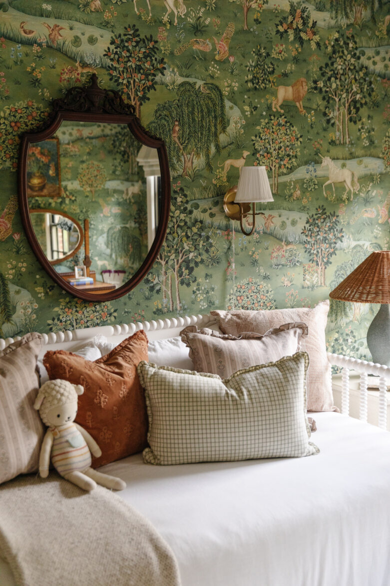 Elegant bedroom featuring a vintage-inspired wallpaper with woodland animals and lush greenery, complemented by a white bed adorned with cozy pillows and a plush teddy bear.