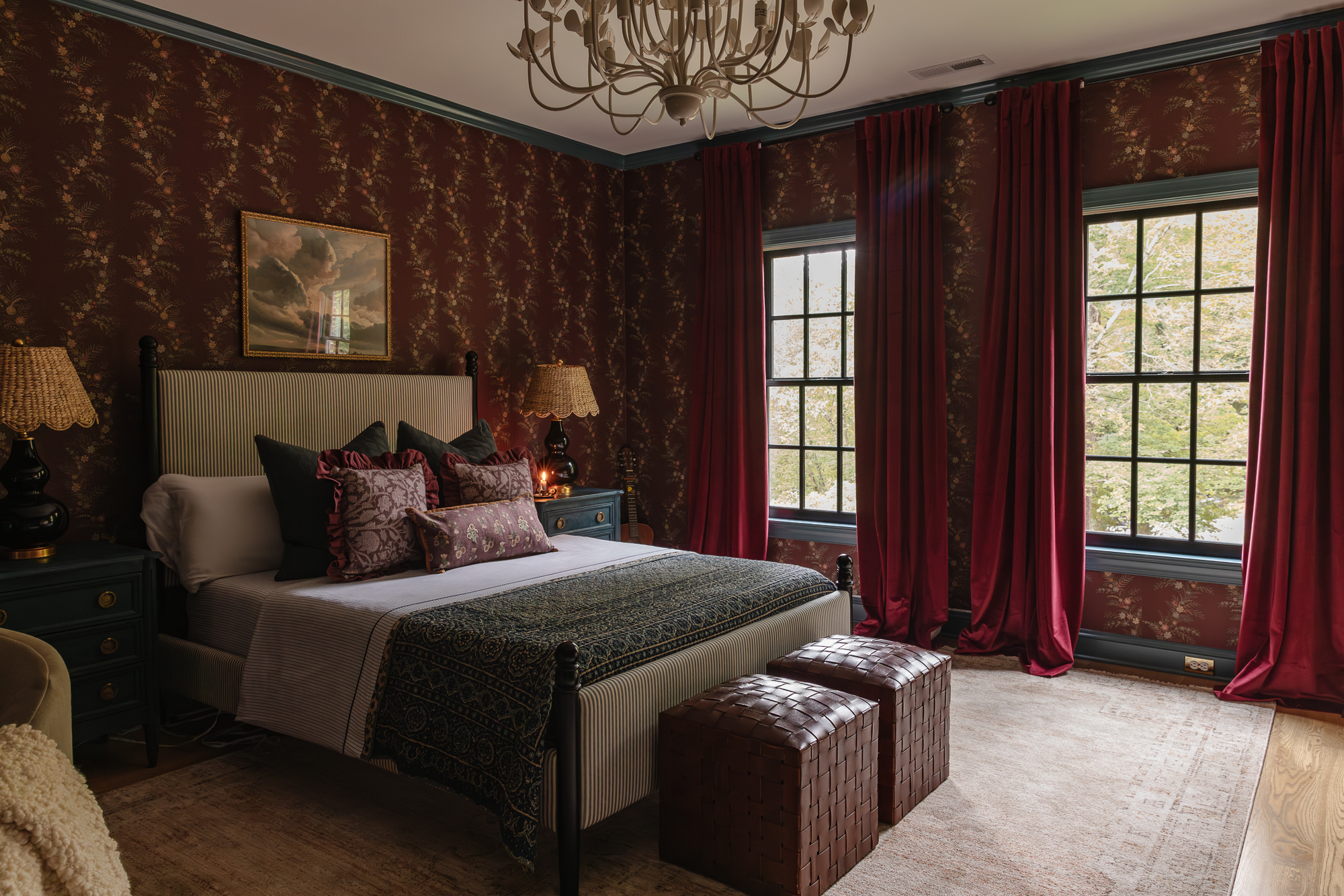 Beautifully decorated bedroom with dark patterned wallpaper, large windows with red curtains, and a cozy, elegant ambiance.