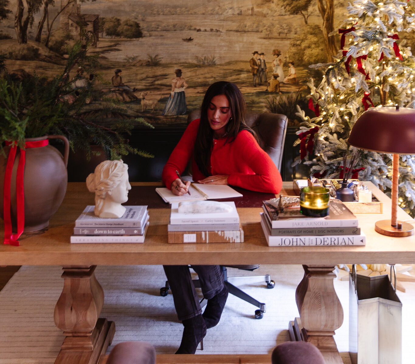 Julia in a red sweater sitting at the desk in the Study writing a card