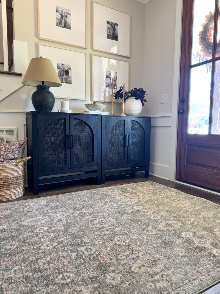 Elegant dark blue vintage-inspired sideboard with woven cabinet doors, styled with decorative lamps, candle holders, and houseplants in a cozy, modern farmhouse entryway.