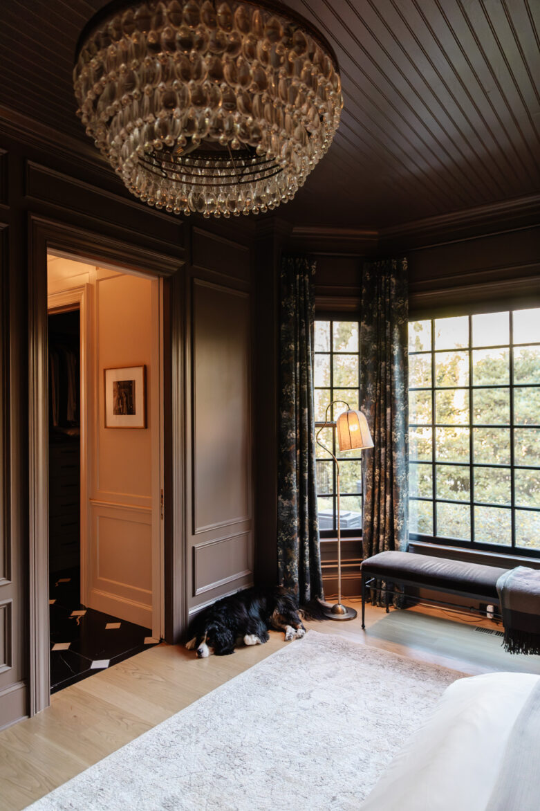 Bedroom interior with large windows, dark wood accents, and statement lighting, highlighting stylish home decor and renovation inspiration.