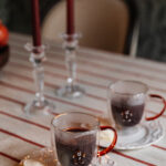 Beautiful holiday scene featuring cookies, candles, and warm beverages on a festive table.