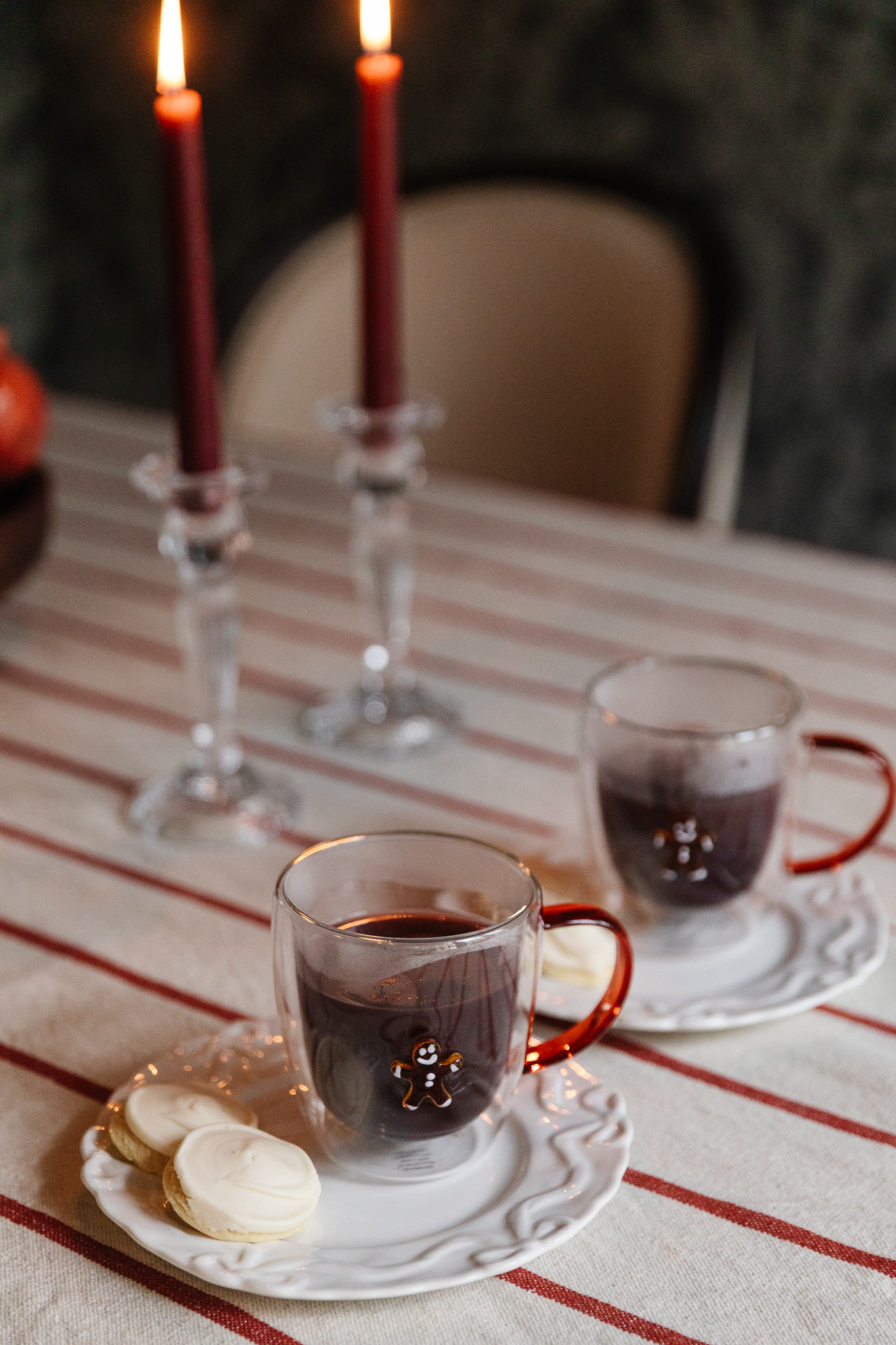 Beautiful holiday scene featuring cookies, candles, and warm beverages on a festive table.