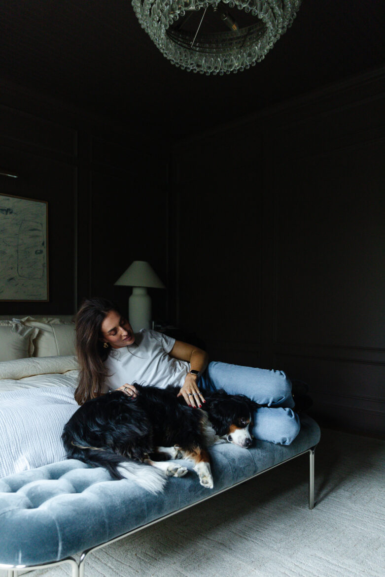 Julia casually reclined on a bench by the bed with her Bernese Mountain Dog Cricket. 