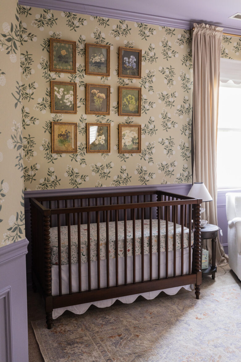 A beautifully decorated nursery room with floral wallpaper, a white armchair, and warm wood furniture, perfect for a cozy and stylish nursery.