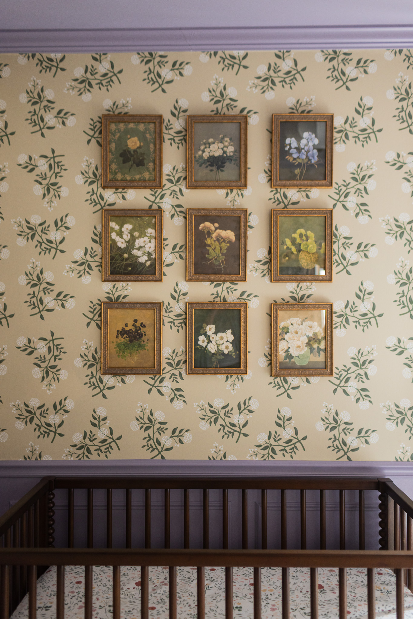 Beautiful floral artwork framed on a wall with vintage-style floral wallpaper, creating a charming and cozy nursery space.