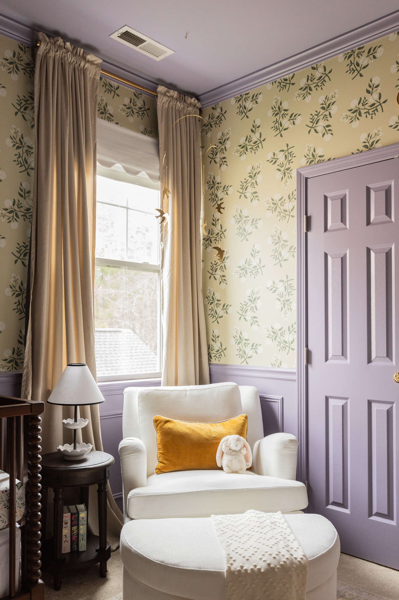 Bright room with purple accents, featuring a white armchair, plush pillows, and matching ottoman, perfect for relaxing or reading with natural light streaming through the window.