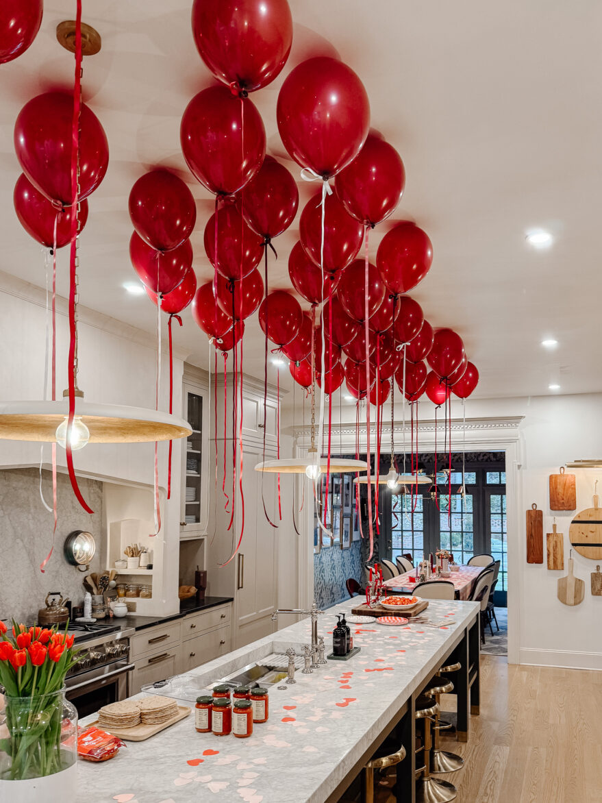 Bright red balloons fill the kitchen ceiling with ribbons hanging down for festive decor.