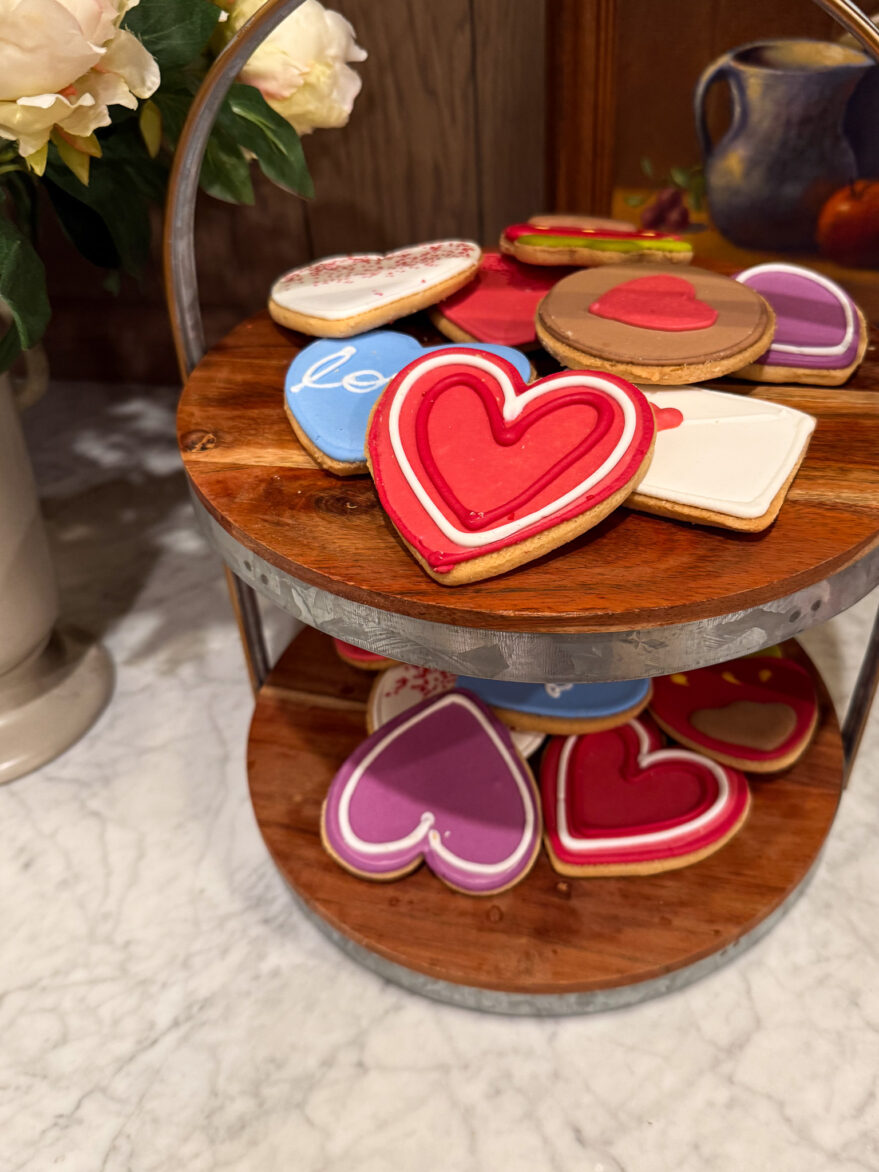 Decorated heart-shaped cookies on a wooden and metal stand, perfect for Valentine's Day or romantic celebrations, featuring vibrant icing designs and colorful patterns.