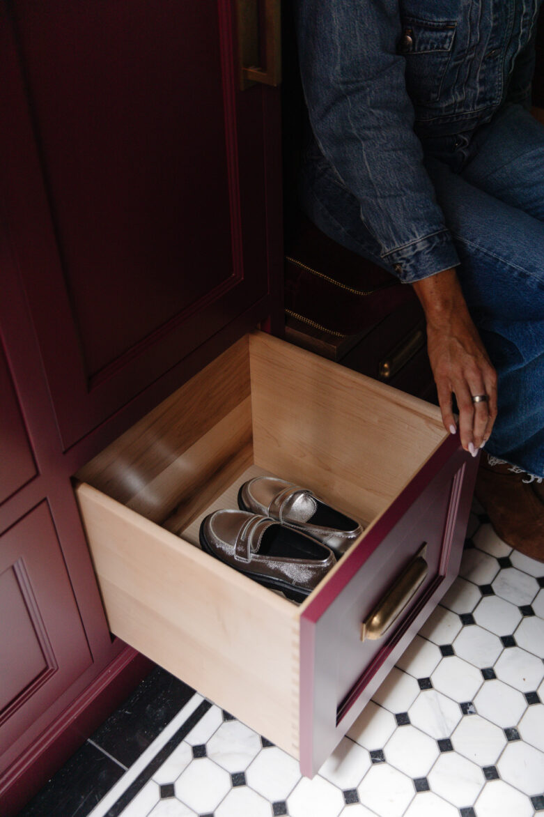 Close-up of a modern shoe storage drawer with silver shoes, set in a custom red kitchen cabinet, showcasing organization and interior design.