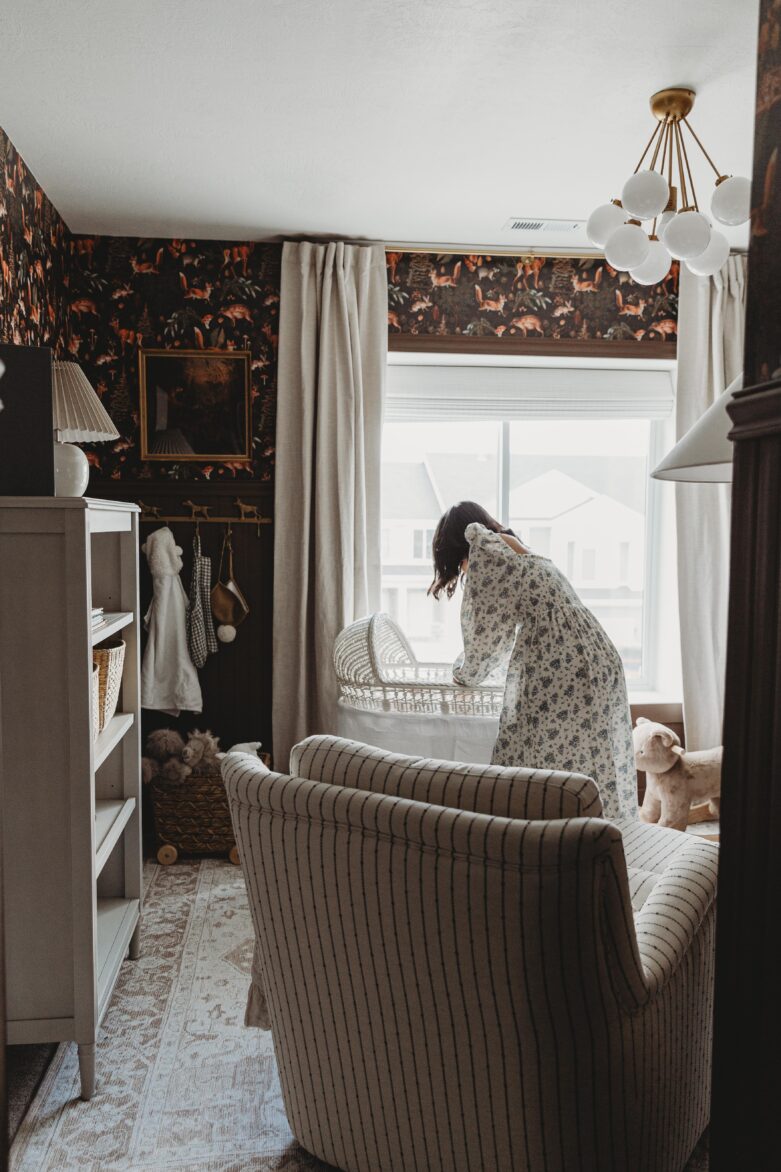 Bright nursery with vintage wallpaper, cozy armchair, and large window for perfect baby nursery design inspiration.