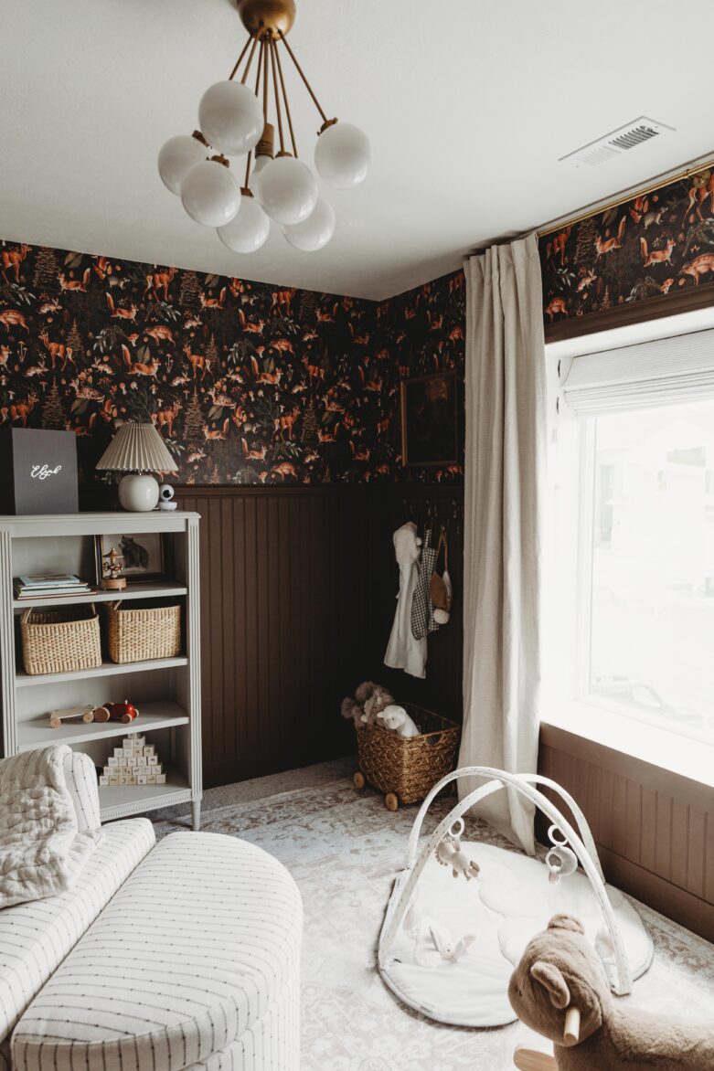 Bright nursery with dark woodland-themed wallpaper, white accents, and natural light, showcasing home decorating tips from Chris Loves Julia.