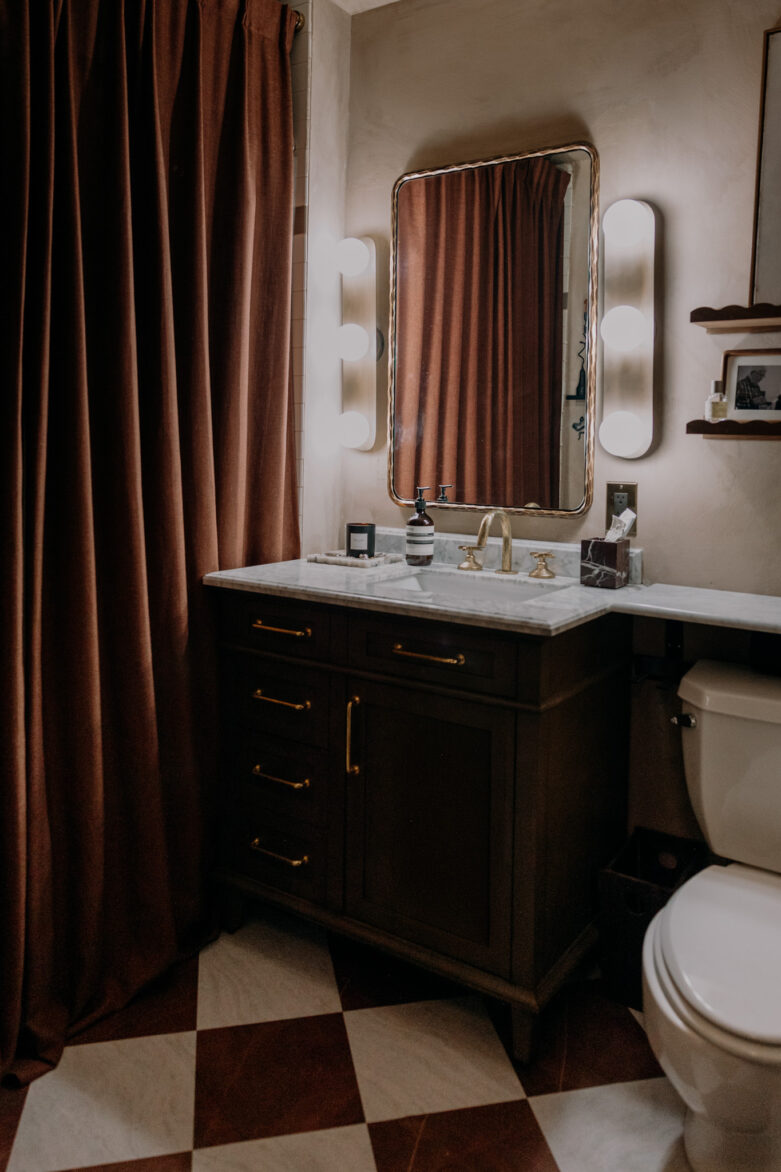 Stylish bathroom featuring a dark wood vanity, large mirror, and peel-and-stick floor tiles in a diamond pattern, creating a contemporary and inviting space.