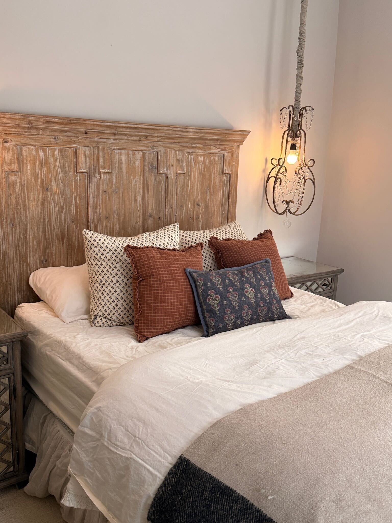 Comfortable bed with layered pillows in a rustic lakehouse bedroom featuring a wooden headboard and warm lighting. Perfect for relaxing getaways.