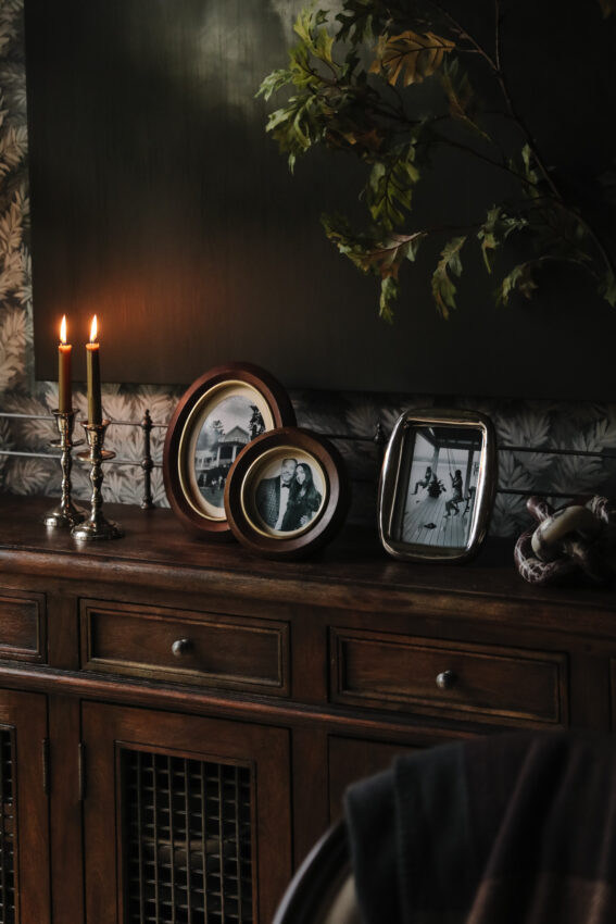 Vintage wooden sideboard decorated with candles and framed black-and-white photos.