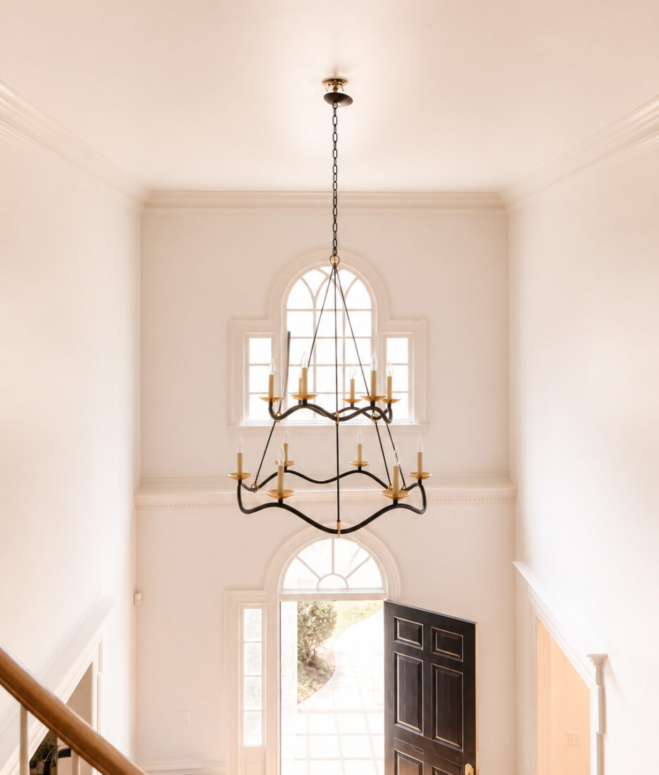 Bright and airy entryway featuring a large arched window, black front door, and a stunning black chandelier, creating a welcoming and stylish entrance.