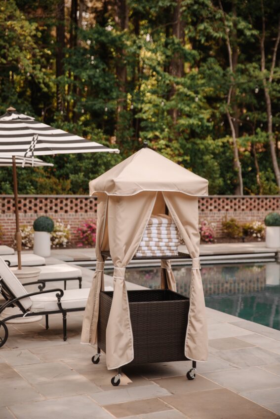 Outdoor poolside cabana with beige curtains, a cushioned lounge chair, and surrounding pool area, perfect for relaxing and enjoying outdoor leisure activities.
