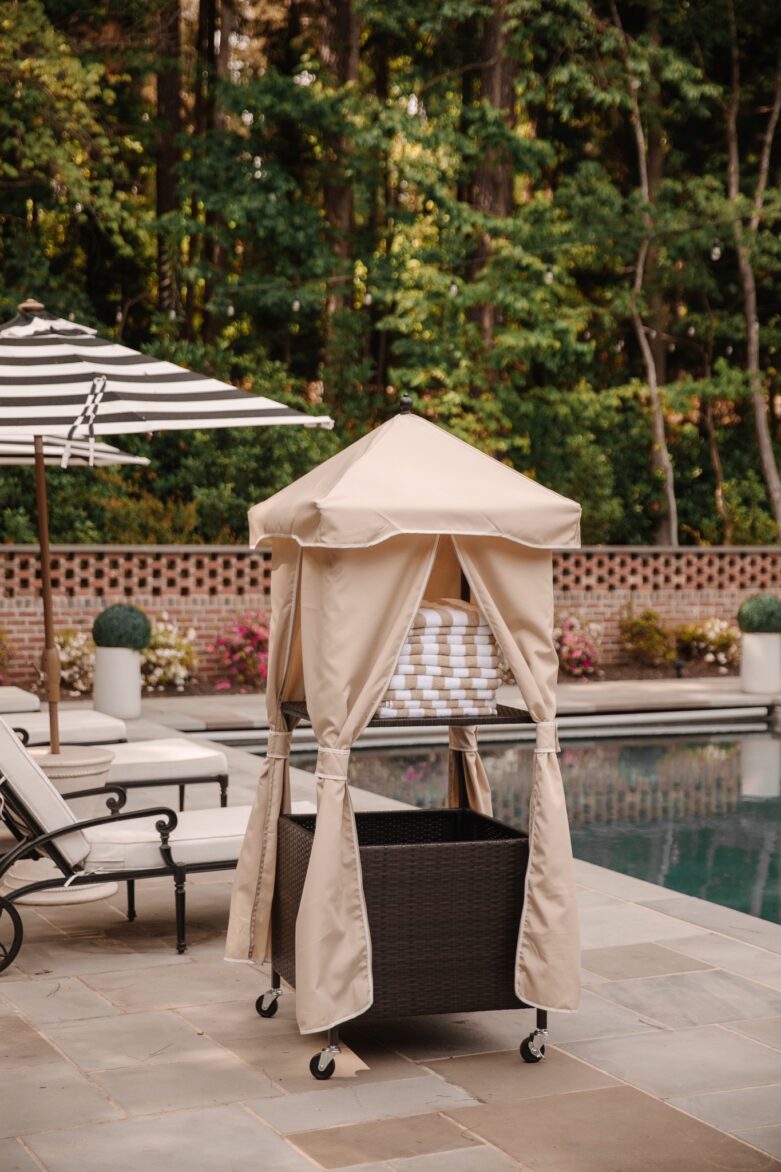 Outdoor poolside cabana with beige curtains, a cushioned lounge chair, and surrounding pool area, perfect for relaxing and enjoying outdoor leisure activities.