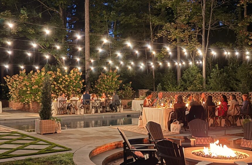 Outdoor backyard with string lights, fire pit, and seating area at night.