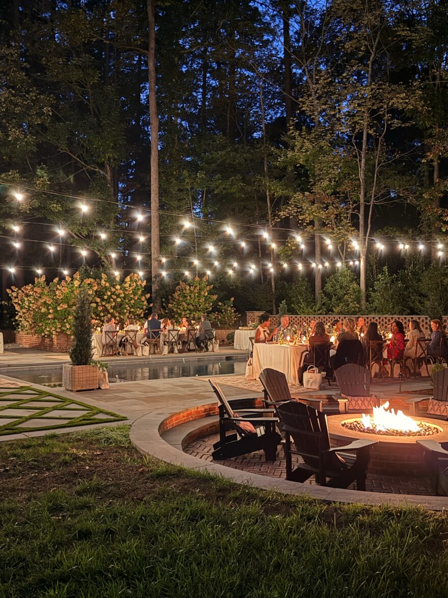 Outdoor backyard with string lights, fire pit, and seating area at night.