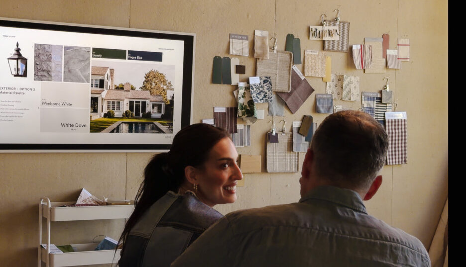 Interior design consultation with a woman and man reviewing color palettes and material samples on a wall display.