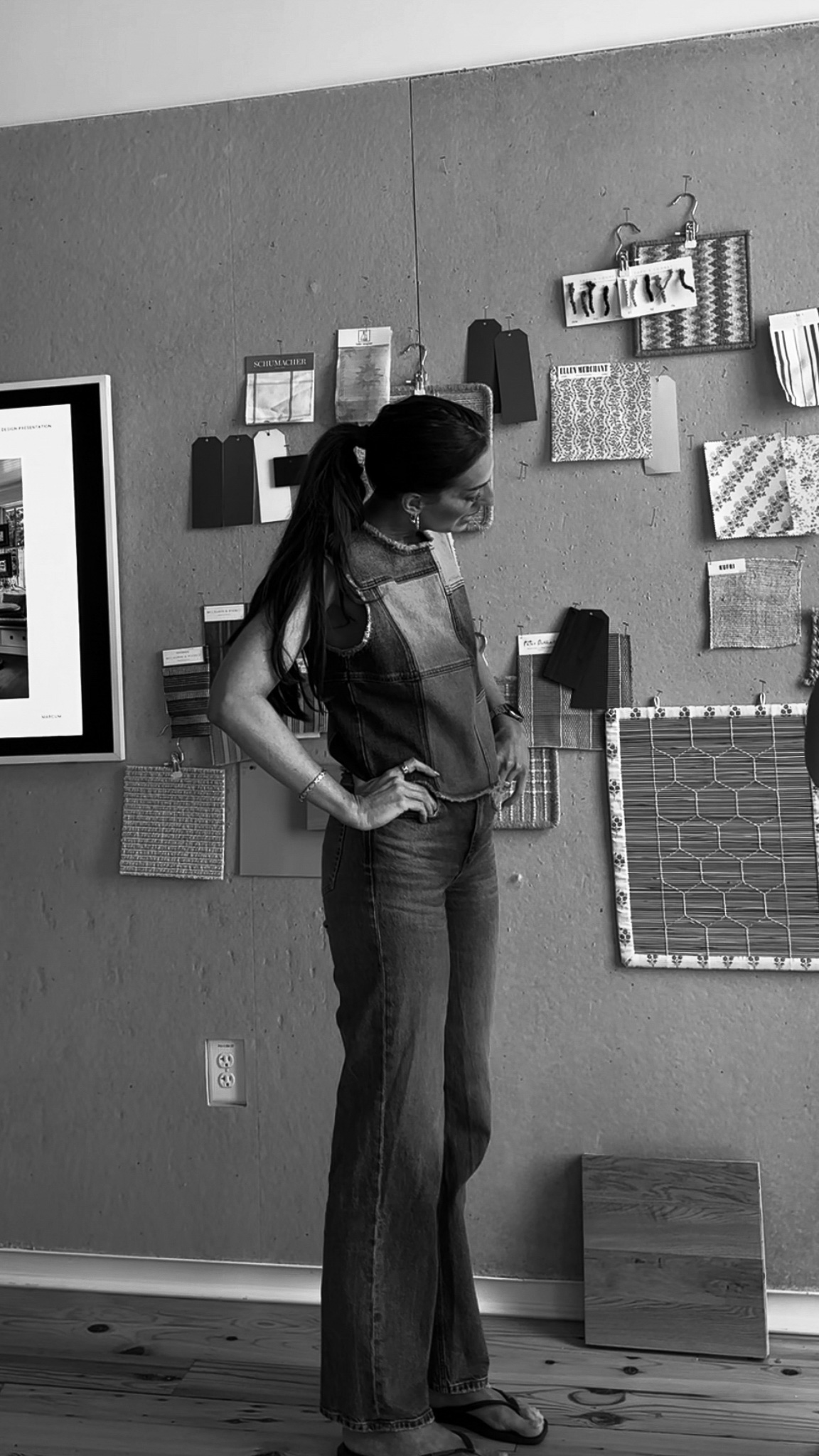 Woman exploring fabric and material samples on display wall in interior design studio, showcasing home decor and renovation ideas.