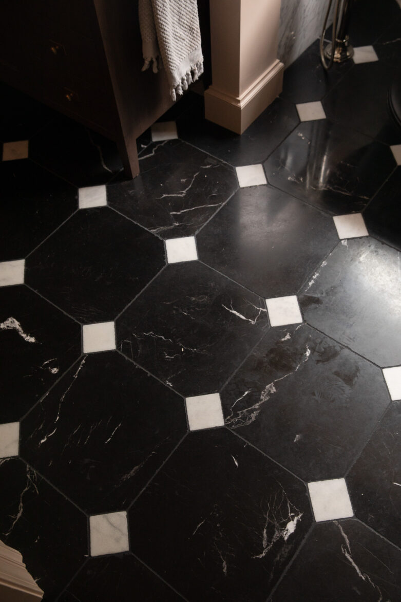 Close-up of a stylish black marble tile floor with white diamond accents in a modern home interior.